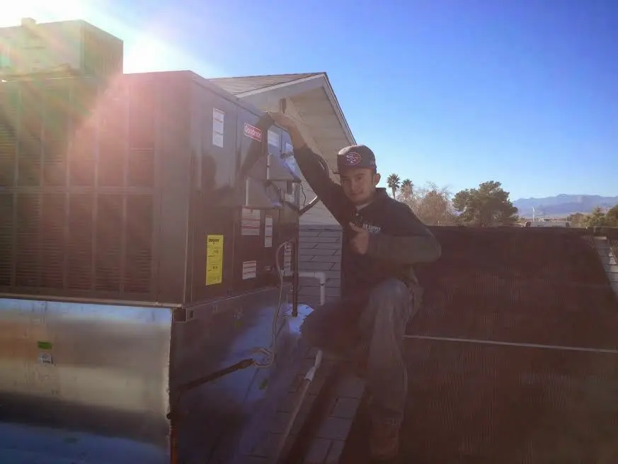 HVAC technician performing Air Duct Cleaning on a rooftop unit in Fenton